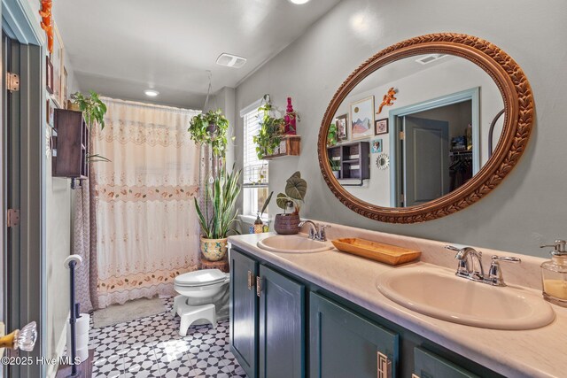 bathroom with double vanity, visible vents, a sink, and toilet