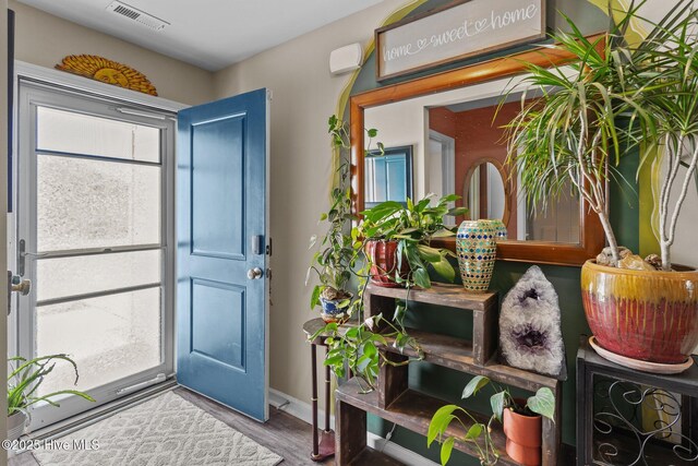 foyer featuring visible vents, baseboards, and wood finished floors