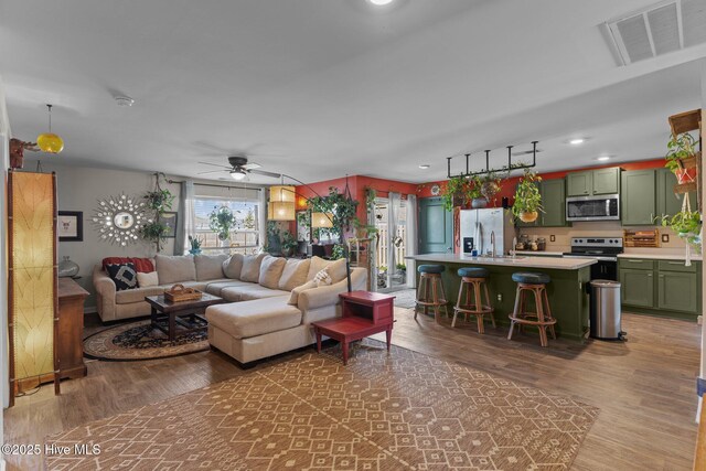 living room with recessed lighting, visible vents, light wood-type flooring, and a ceiling fan