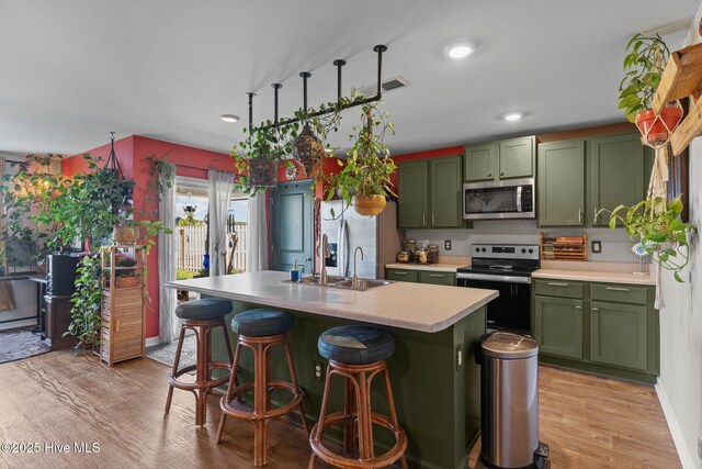 kitchen with light wood-style flooring, light countertops, green cabinetry, and stainless steel appliances