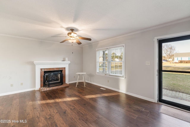 unfurnished living room featuring a brick fireplace, wood finished floors, ornamental molding, and a ceiling fan