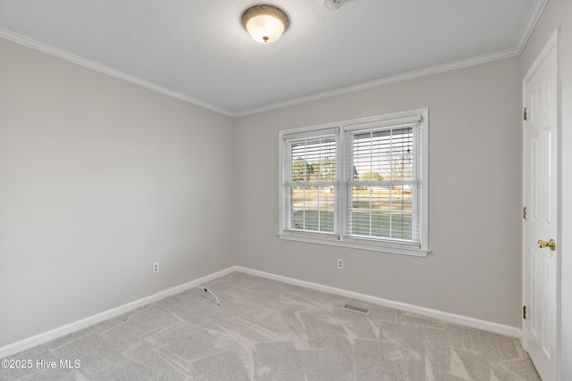 spare room with ornamental molding, baseboards, a textured ceiling, visible vents, and light carpet