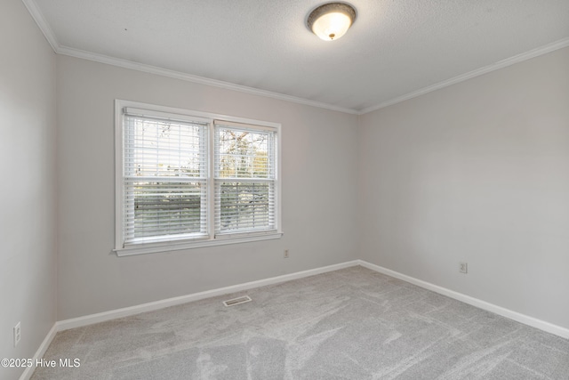 empty room with carpet flooring, a textured ceiling, baseboards, visible vents, and ornamental molding