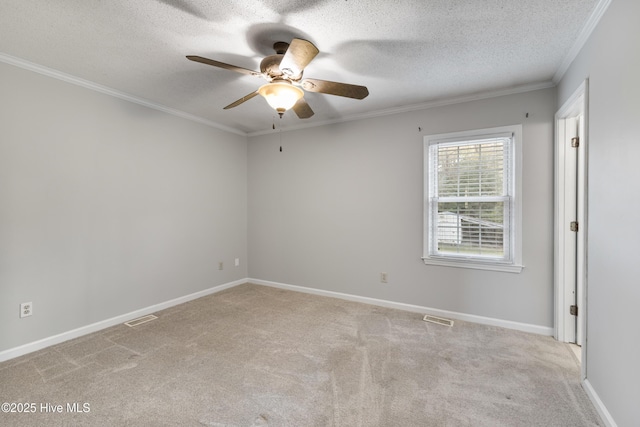 carpeted spare room featuring ornamental molding, baseboards, a textured ceiling, visible vents, and ceiling fan