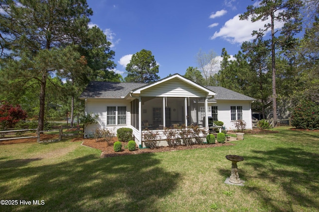 back of property featuring fence, a sunroom, a lawn, and roof with shingles