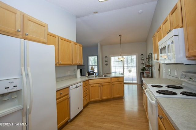 kitchen with a sink, light countertops, white appliances, a peninsula, and light wood-style floors