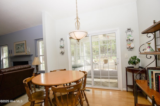 dining room featuring a fireplace, light wood-style floors, and visible vents