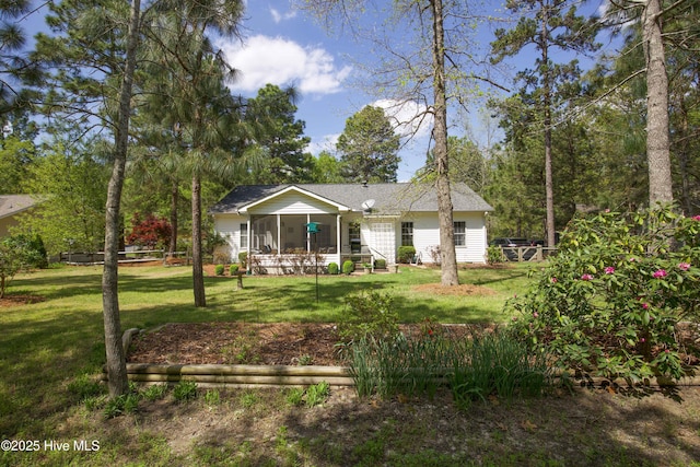 back of property with a sunroom, roof with shingles, and a lawn