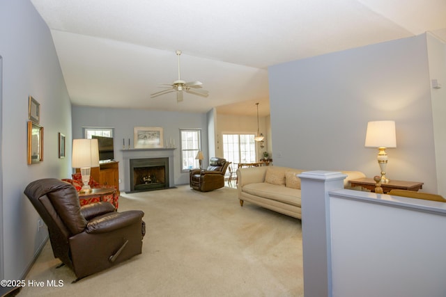 carpeted living room with plenty of natural light, a fireplace with flush hearth, a ceiling fan, and lofted ceiling
