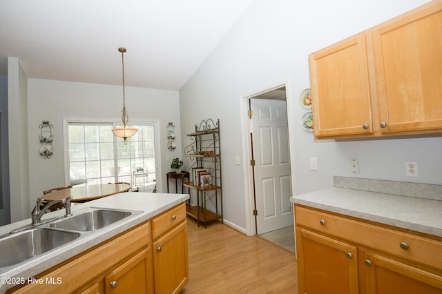 kitchen featuring a sink, light countertops, light wood-style flooring, and pendant lighting