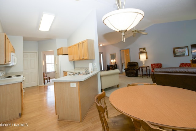 kitchen with open floor plan, light countertops, white appliances, light brown cabinetry, and lofted ceiling