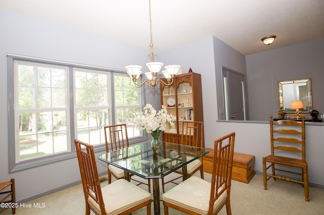 dining room with light colored carpet, an inviting chandelier, and baseboards