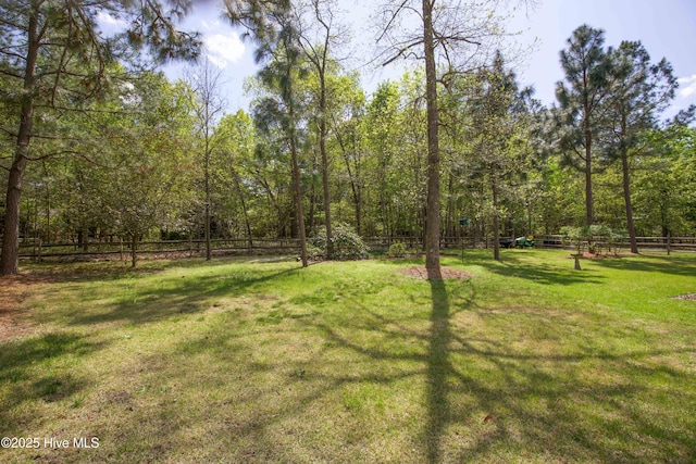 view of yard with a forest view and fence