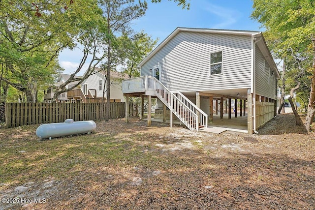 120 NE 27th St, Oak Island, NC 28465 - back of house with a wooden deck, a carport, stairs, and fence