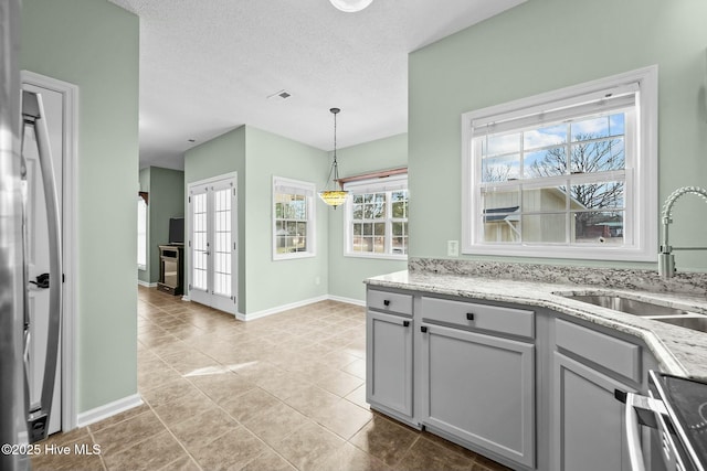 kitchen featuring gray cabinets, a sink, light stone countertops, a textured ceiling, and dishwashing machine