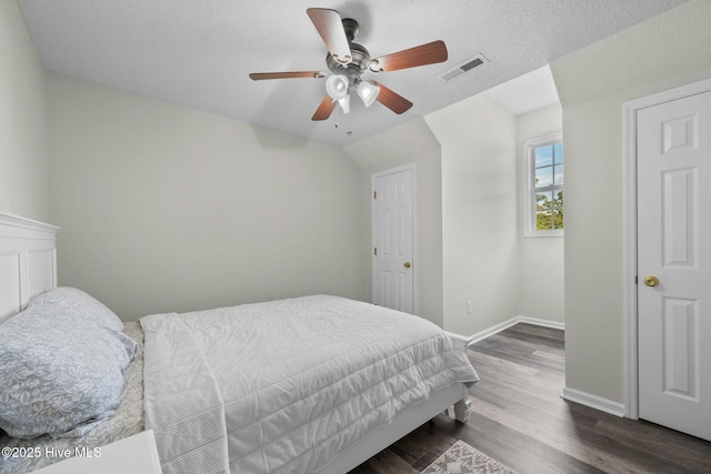 bedroom with dark wood-style flooring, visible vents, baseboards, ceiling fan, and lofted ceiling
