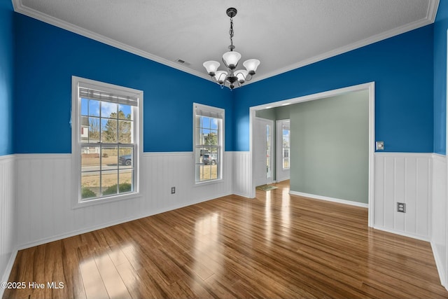 spare room featuring visible vents, a notable chandelier, and wainscoting