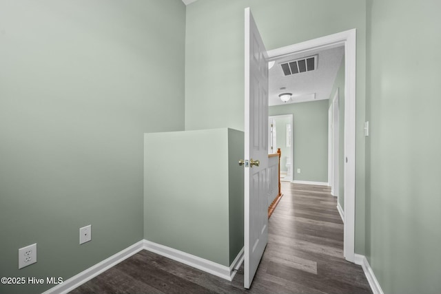 hall with baseboards, visible vents, and dark wood-type flooring