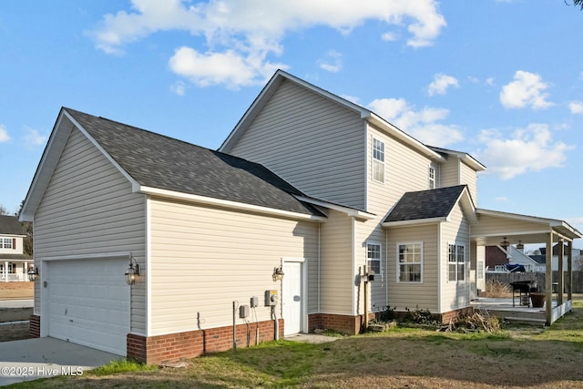exterior space with a lawn, driveway, a shingled roof, and an attached garage