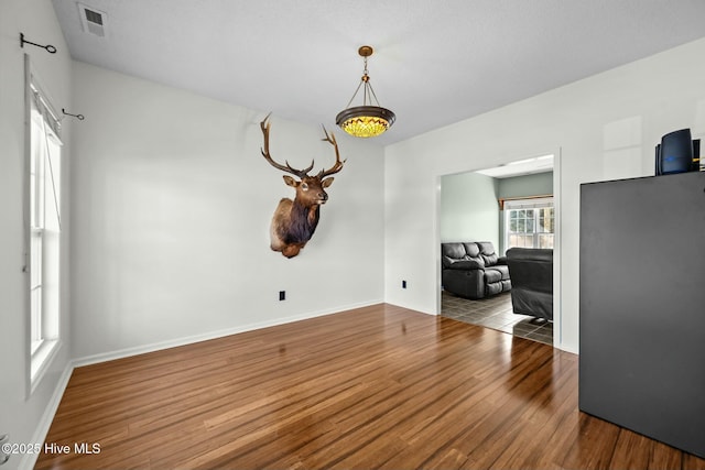 unfurnished dining area with baseboards, visible vents, and wood finished floors