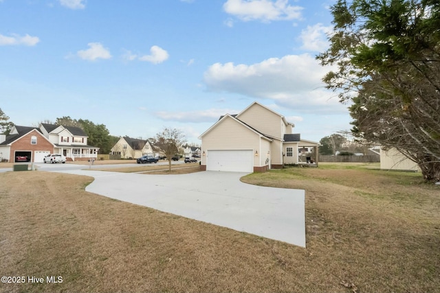 view of yard featuring an attached garage, concrete driveway, and a residential view