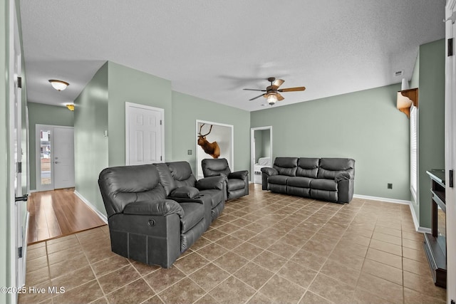 tiled living area with a ceiling fan, baseboards, and a textured ceiling
