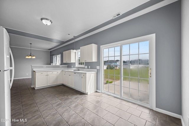 kitchen featuring visible vents, ornamental molding, a peninsula, white appliances, and baseboards