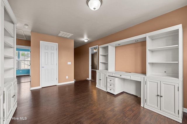unfurnished office featuring visible vents, built in features, baseboards, dark wood-style floors, and built in desk