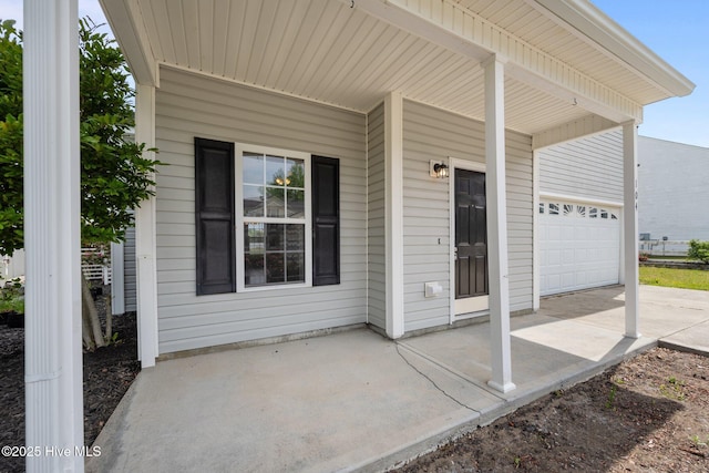 view of patio / terrace featuring concrete driveway, an attached garage, and a porch