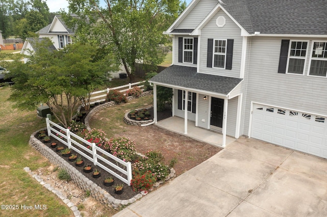 traditional-style home featuring roof with shingles, fence, an attached garage, a porch, and concrete driveway