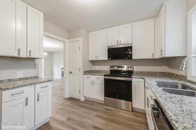 208 Elm St, Whiteville, NC 28472 - kitchen with white cabinetry, a sink, light wood-style floors, and appliances with stainless steel finishes