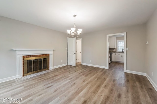 208 Elm St, Whiteville, NC 28472 - unfurnished living room with baseboards, a chandelier, light wood-style floors, and a brick fireplace