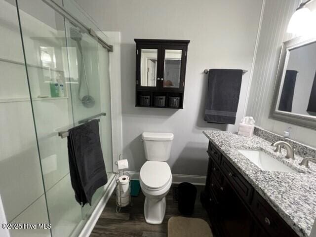 full bath featuring baseboards, toilet, a stall shower, and vanity