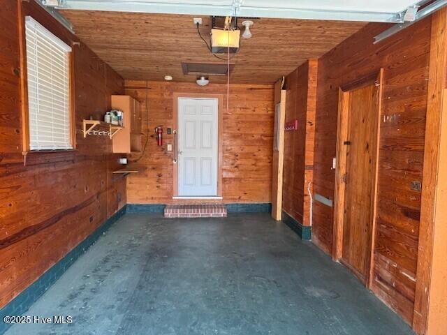 garage featuring wooden ceiling, wood walls, and a garage door opener