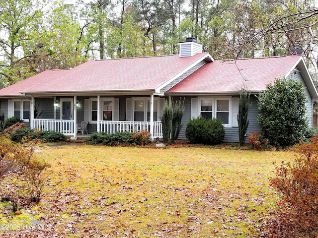 ranch-style house with a porch, a chimney, a shingled roof, and a front yard