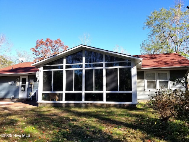 rear view of property with a sunroom and a lawn
