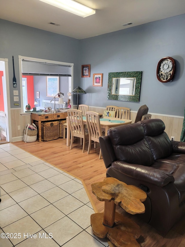 living area featuring visible vents, wood finished floors, and a wainscoted wall