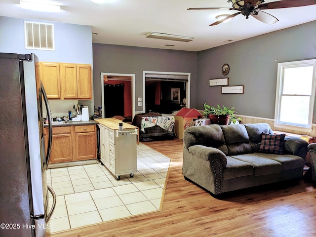 living room featuring a ceiling fan, visible vents, and light wood-style flooring