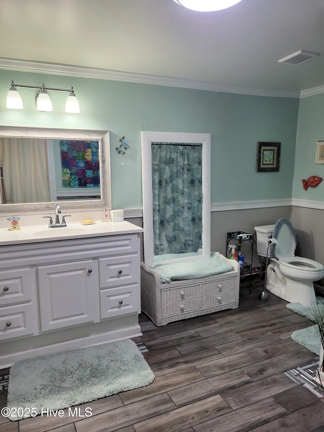 full bathroom featuring vanity, ornamental molding, visible vents, wood finished floors, and toilet