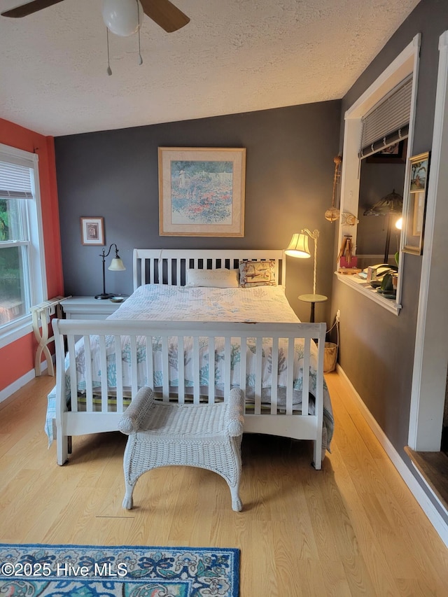bedroom featuring a textured ceiling, baseboards, and wood finished floors