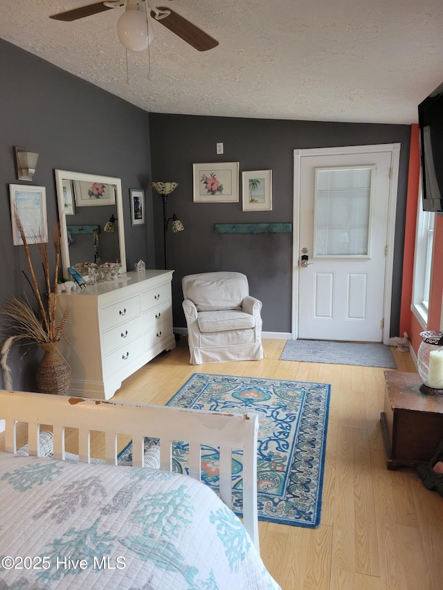 bedroom featuring a textured ceiling, a ceiling fan, and light wood-style flooring