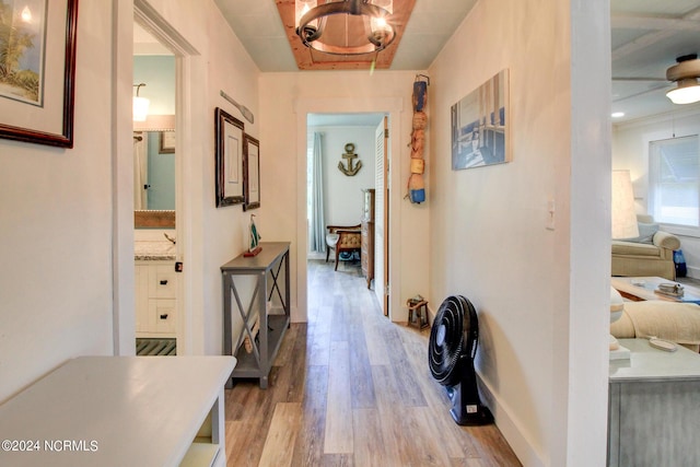 corridor with baseboards, a notable chandelier, and light wood finished floors