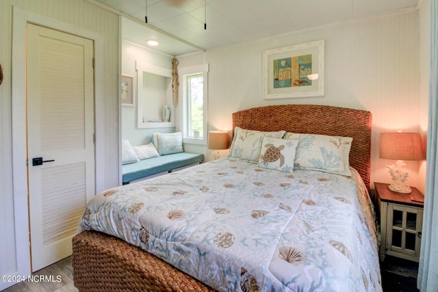 bedroom with wood finished floors and crown molding