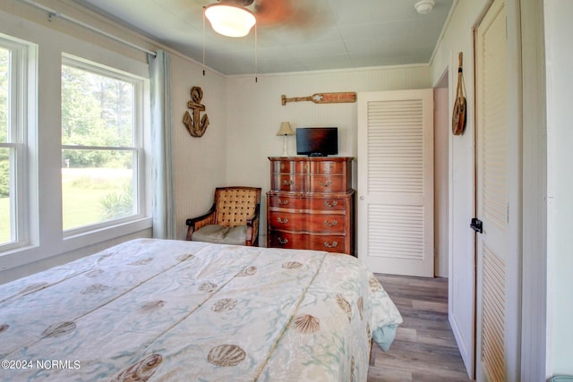 bedroom with crown molding, wood finished floors, and multiple windows