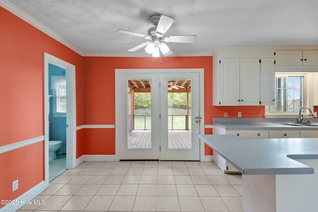doorway to outside featuring a sink, baseboards, a ceiling fan, crown molding, and light tile patterned flooring