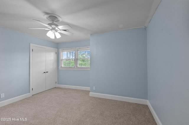 unfurnished bedroom featuring carpet flooring, a closet, baseboards, and a ceiling fan