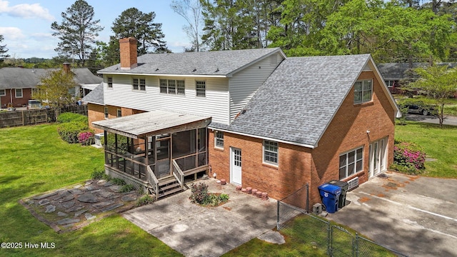 rear view of house with a sunroom, a patio, a chimney, brick siding, and a shingled roof