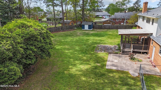 view of yard featuring a patio, a residential view, a storage shed, an outdoor structure, and a sunroom