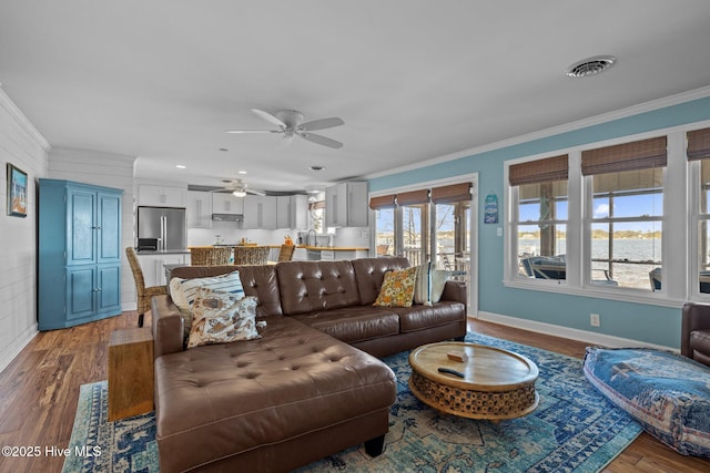 living room with wood finished floors, visible vents, crown molding, and ceiling fan
