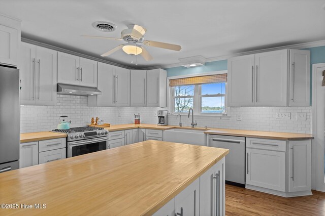 kitchen featuring visible vents, appliances with stainless steel finishes, wooden counters, and under cabinet range hood